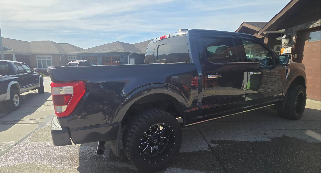Clean black pickup truck parked in a driveway after detailing